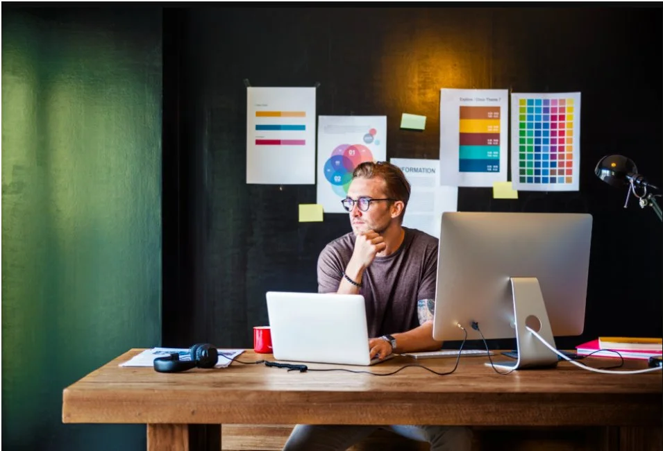 A professional graphic designer brainstorming the benefits of custom website design for businesses in a creative workspace with mood boards.