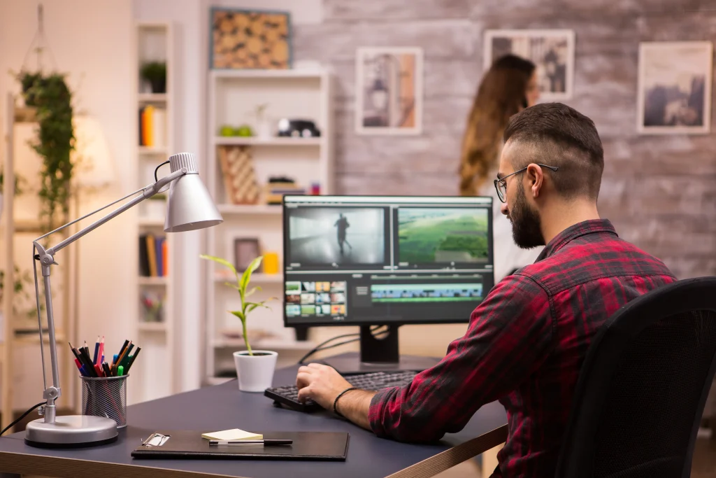 A male content creator sitting at a desk, learning how to convert video to animation. He is using professional software on a large monitor, demonstrating the process of "The Magic of Motion: How to Turn Video into Animation."