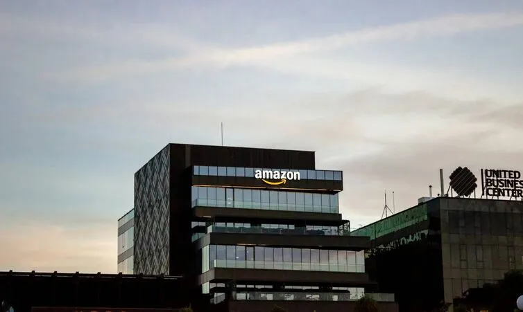 Amazon office building with illuminated company logo at sunset