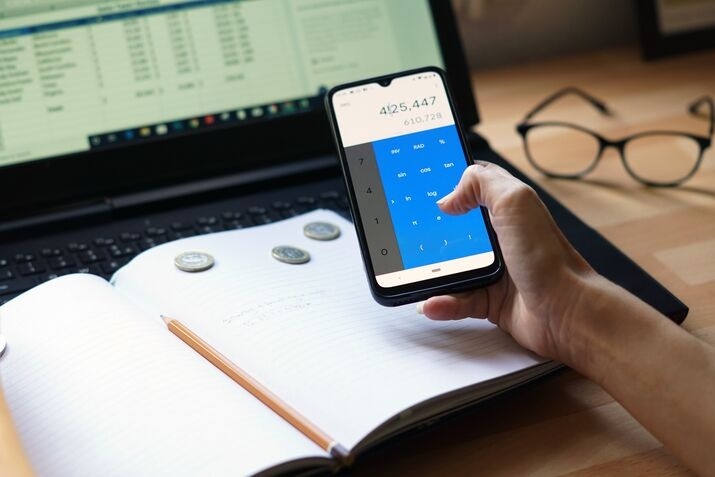 Person using a smartphone calculator to estimate mobile app development costs
